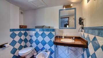 Een badkamer met toilet, bidet en wastafel.
