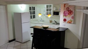 Eine kleine Küche mit Kühlschrank, Mikrowelle, Spüle und einer kleinen Bar.