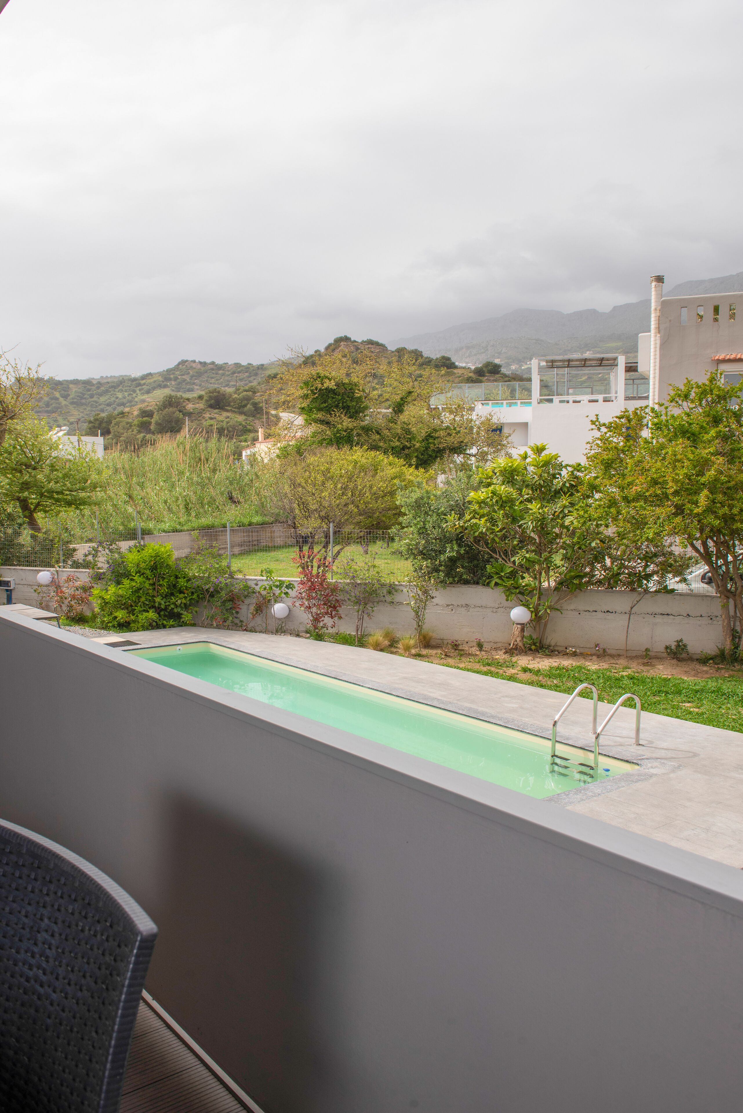 A swimming pool with a view of a hilly landscape and a building in the background.