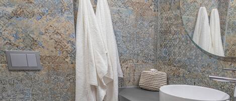 Un baño con pared con diseño de mármol, un inodoro, un lavabo y un espejo.