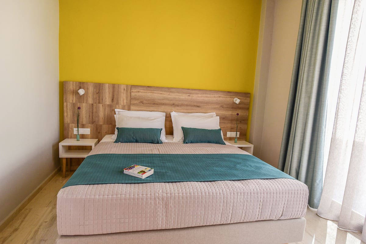 A neatly made bed with a teal blanket, two white pillows, and a book on the bed.