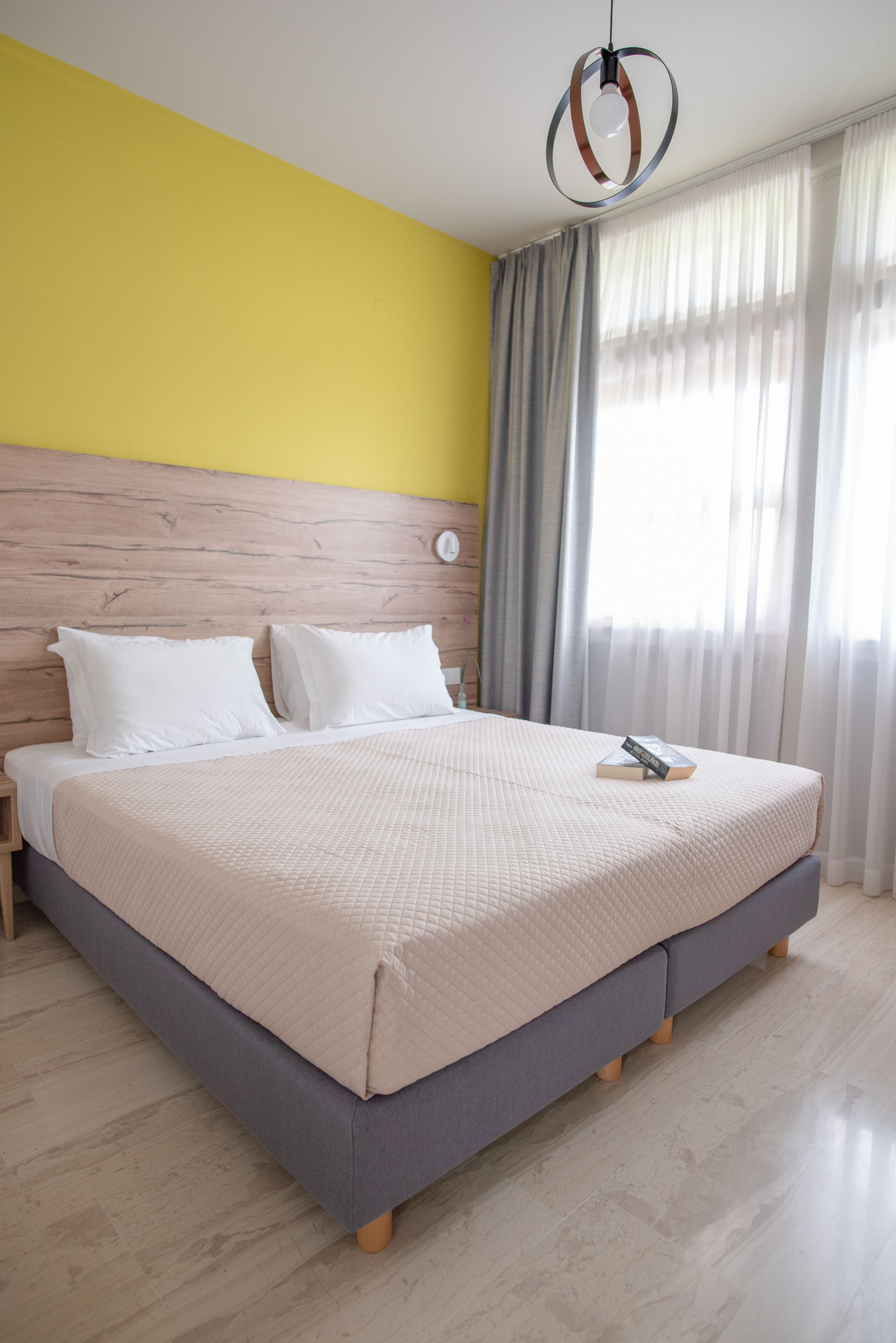 Una cama grande con cabecera de madera, una mesita de noche y un libro sobre la cama.