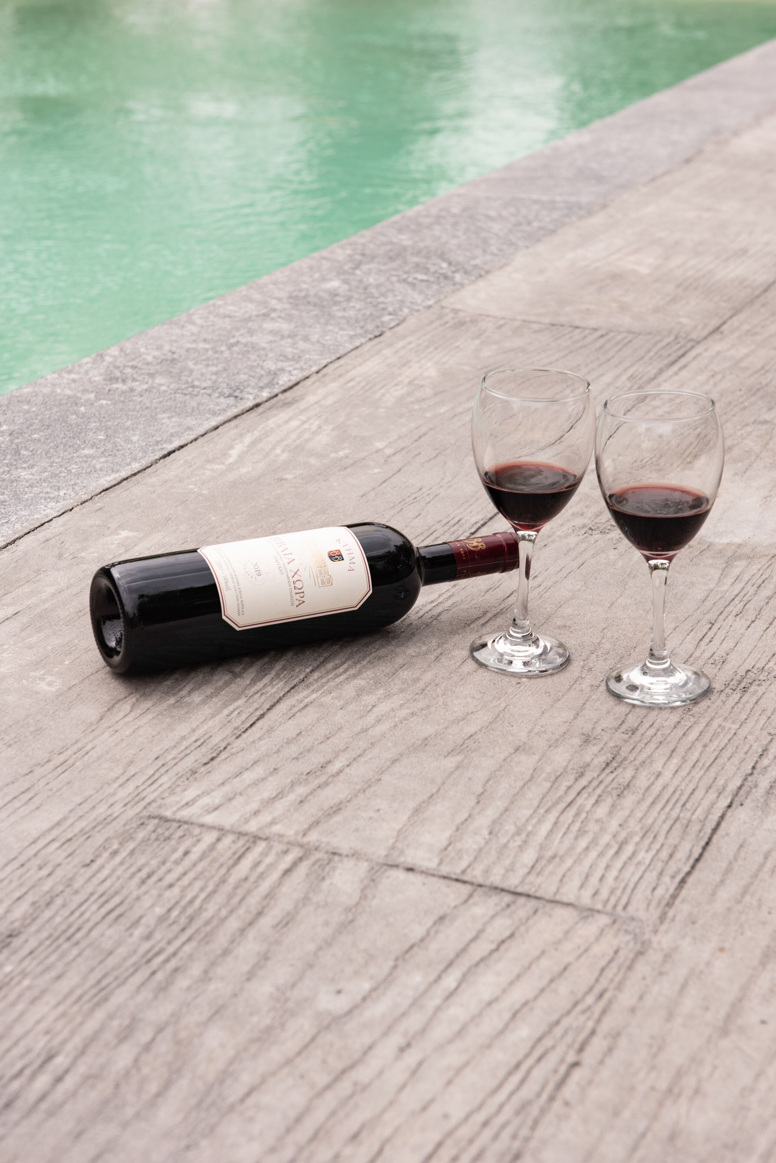 Una bottiglia di vino su un tavolo di legno, accanto a due bicchieri da vino.