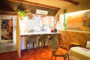 Una cocina acogedora con barra, que incluye un mostrador, taburetes y una planta colgante.