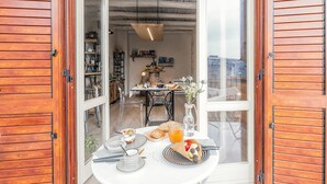 Una mesa de desayuno con diversos alimentos, un florero con flores y una lámpara colgante en un ambiente de cocina moderno.
