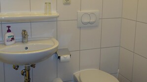 Une salle de bain avec un lavabo blanc, un miroir et des toilettes.
