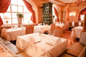 A restaurant with multiple tables set for dining, each with white tablecloths and cutlery.