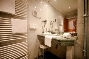 Une salle de bain moderne avec un plan de toilette en marbre, un lavabo, un miroir et un porte-serviettes.