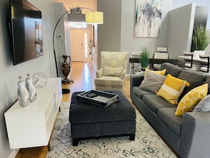 Relax in this stylish living room with a comfortable sofa, patterned armchair, and flat-screen TV.