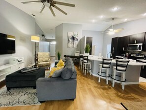 Relax in a spacious living area with a sofa and ottoman, dining area with a small island, and a fully equipped kitchen.