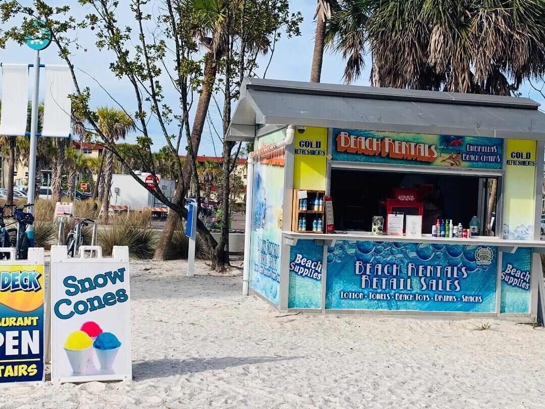 A beach rental kiosk with a sign for snow cones and a deck rental sign.