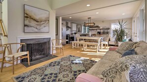 A spacious living room with a fireplace, a dining area, and a kitchen in the background. - Kayaks, Deck & Pond Access: Rhode Island Retreat! (South Kingstown)