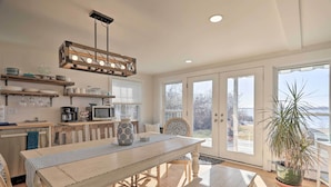 A spacious kitchen with wooden cabinetry, a central island, and a hanging light fixture. - Kayaks, Deck & Pond Access: Rhode Island Retreat! (South Kingstown)