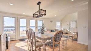 A dining area with a wooden table, chairs, and a hanging light fixture. - Kayaks, Deck & Pond Access: Rhode Island Retreat! (South Kingstown)
