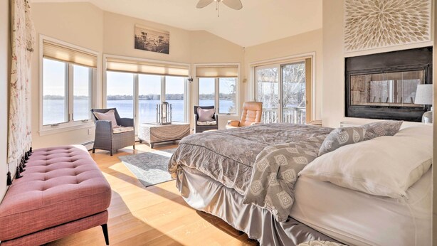 A spacious bedroom with a large bed, a seating area with chairs, and a view of the outdoors. - Kayaks, Deck & Pond Access: Rhode Island Retreat! (South Kingstown)