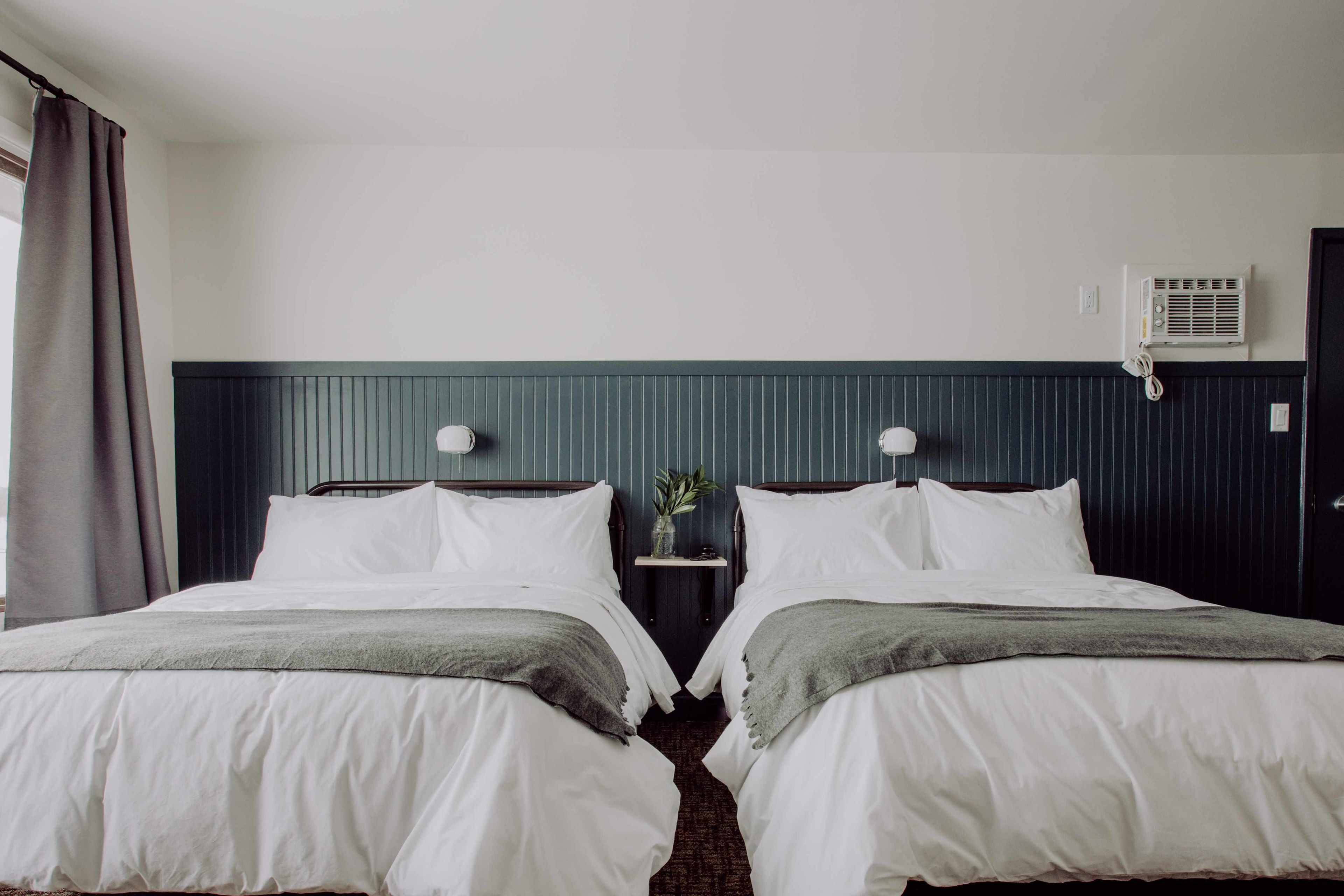 A double bed with a dark headboard, white bedding, and a small bedside table with a vase.