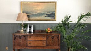 Un bureau en bois, une lampe, une machine à café et un saladier rempli de fruits.