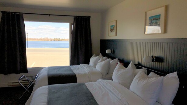 Une chambre d’hôtel avec deux lits, une vue sur la plage et un tableau encadré au mur.