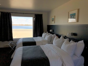 Habitación de hotel con dos camas, vista a la playa y un cuadro en la pared.