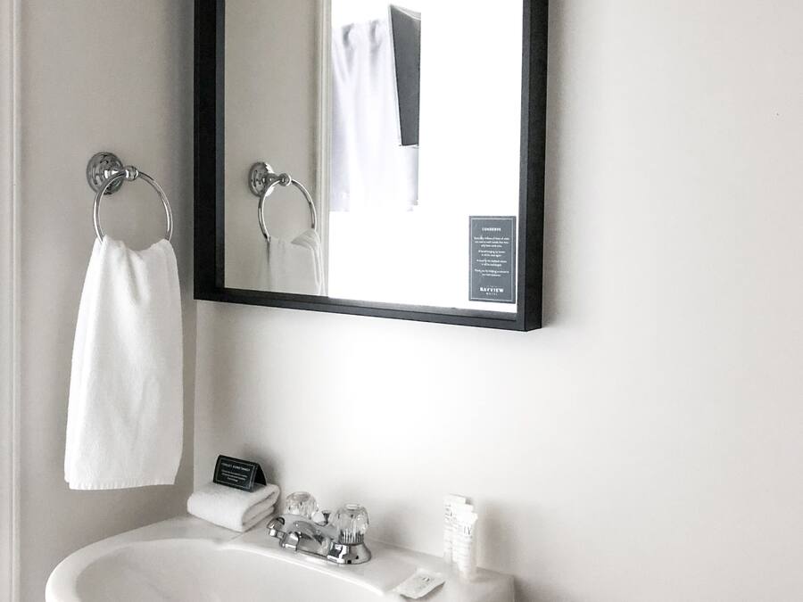 Une salle de bain avec un lavabo blanc, un miroir et un porte-serviettes.