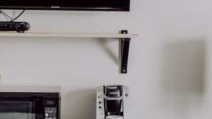 Une petite cuisine équipée d’un four à micro-ondes, d’une machine à café et d’un petit réfrigérateur.