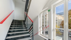 A modern staircase with black and white steps, red handrails, and a glass door leading outside. - Kapsuła Hostel Warszawa (Warsaw)