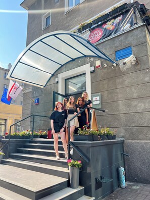 A group of people standing on a staircase outside a building with a glass canopy. - Kapsuła Hostel Warszawa (Warsaw)