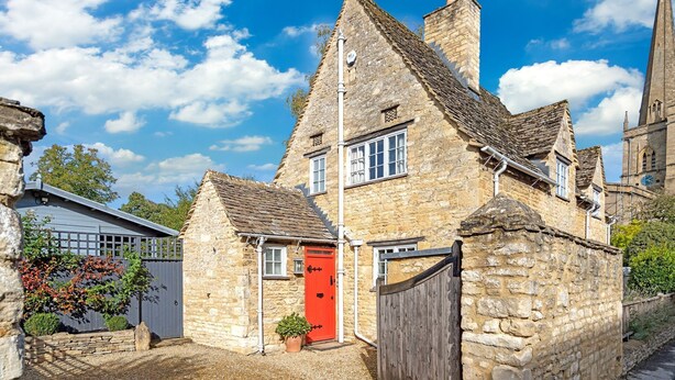 A stone building with a red door, a small window, and a chimney. - Church Cottage - sleeps 6 guests  in 3 bedrooms (Burford)