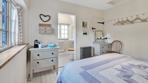 A bedroom with a bed, a dresser, a vanity, and a window with curtains. - Church Cottage - sleeps 6 guests  in 3 bedrooms (Burford)