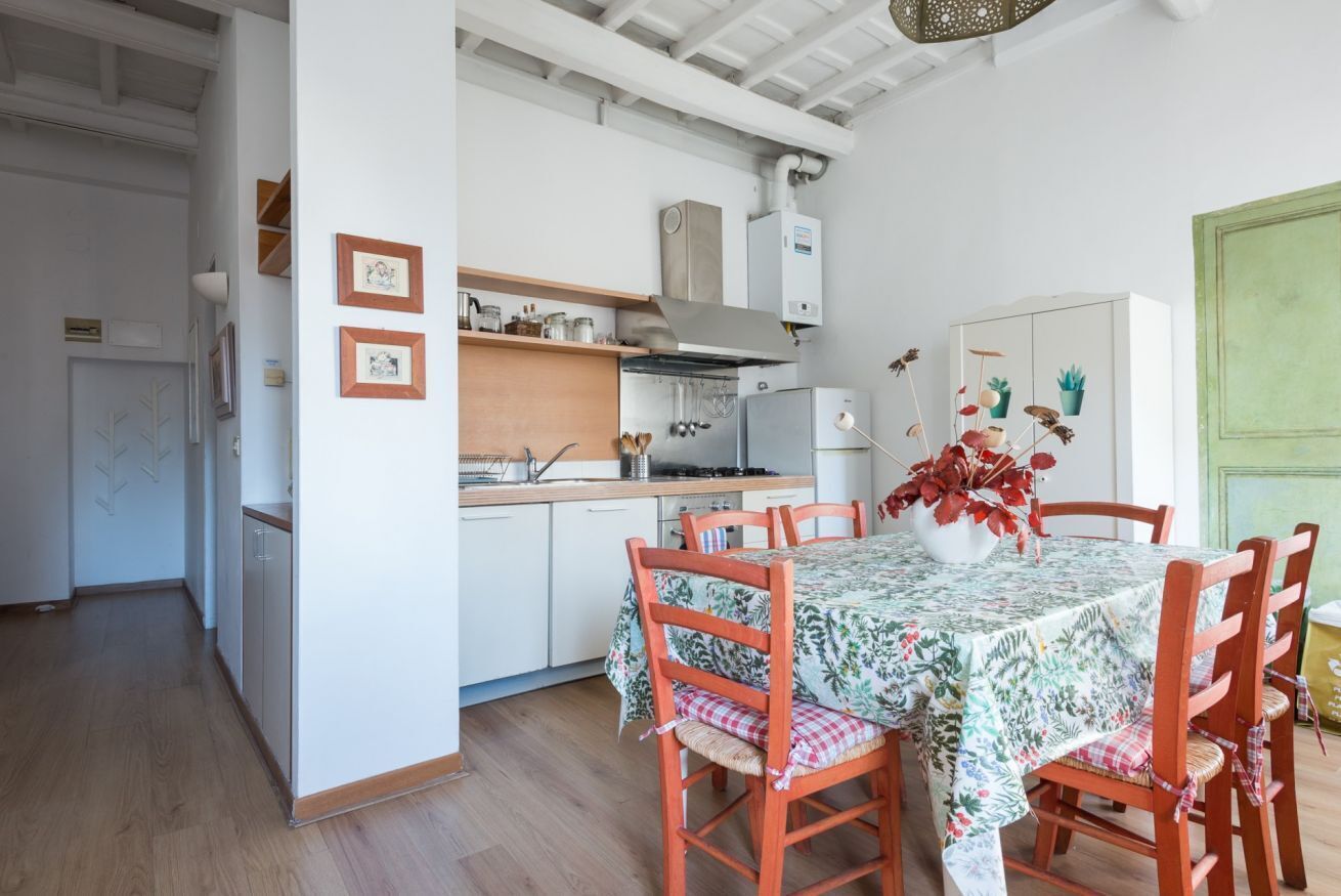 A kitchen with white cabinets, a wooden countertop, and a dining table with chairs.