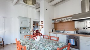 Cozinha com armários brancos, fogão de aço inoxidável e mesa de jantar com cadeiras.