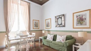 A room with a dining table, chairs, a green sofa, and a mirror. - Navona Charming Terrace Apartment (Rome)