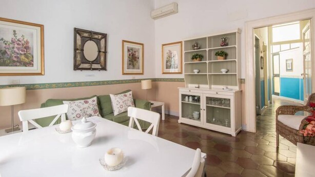 A dining area with a white table, chairs, and a cabinet with glass doors. - Navona Charming Terrace Apartment (Rome)