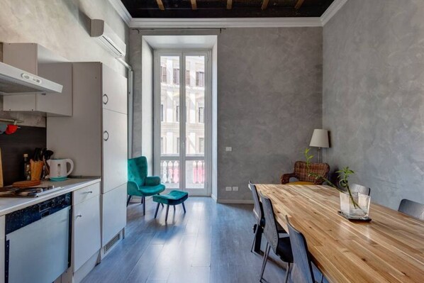 Eine moderne Küche mit weißen Schränken, einem Holztisch und türkisfarbenen Stühlen.