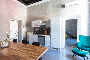 Eine moderne Küche mit weißen Schränken, einem Holztisch und einem blaugrünen Stuhl.