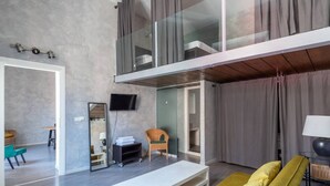 En modern inredning med en soffa, en platt-TV, ett litet bord och en stol.