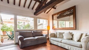 A living room with a grey sofa, a striped sofa, a wooden ceiling, and a large window. - Campo de Fiori Luxury House (Rome)