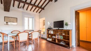 A dining area with a wooden table and chairs, a bookshelf, and a television. - Campo de Fiori Luxury House (Rome)