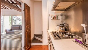 A kitchen with a gas stove, kettle, and shelves with kitchen items. - Campo de Fiori Luxury House (Rome)