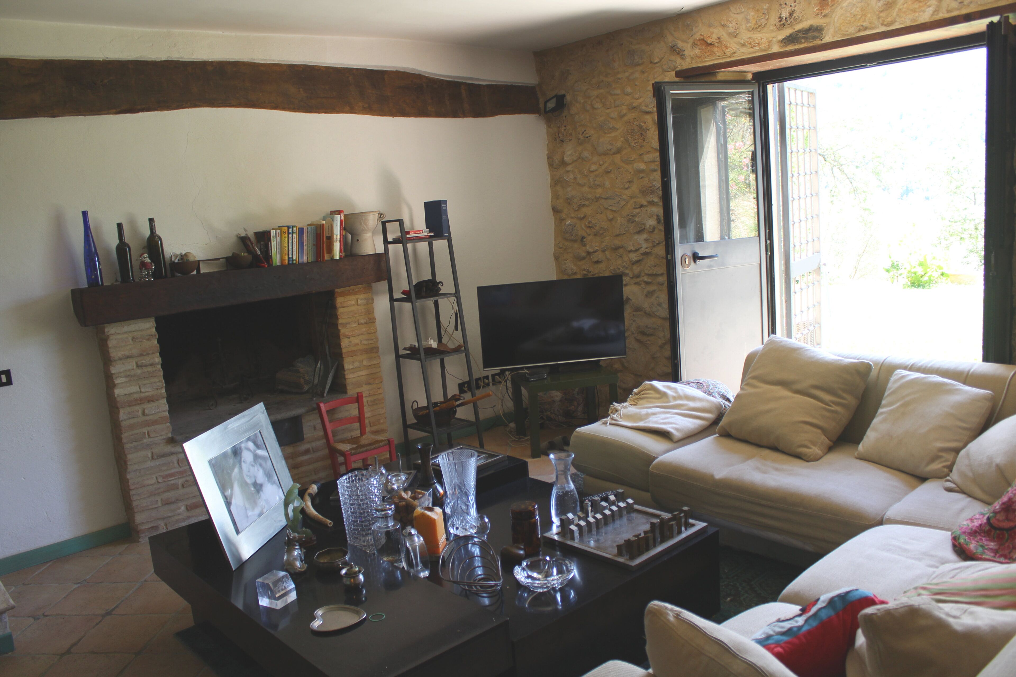 Ein Wohnzimmer mit Kamin, einer Couch, einem Fernseher und einem Couchtisch mit verschiedenen Gegenständen.