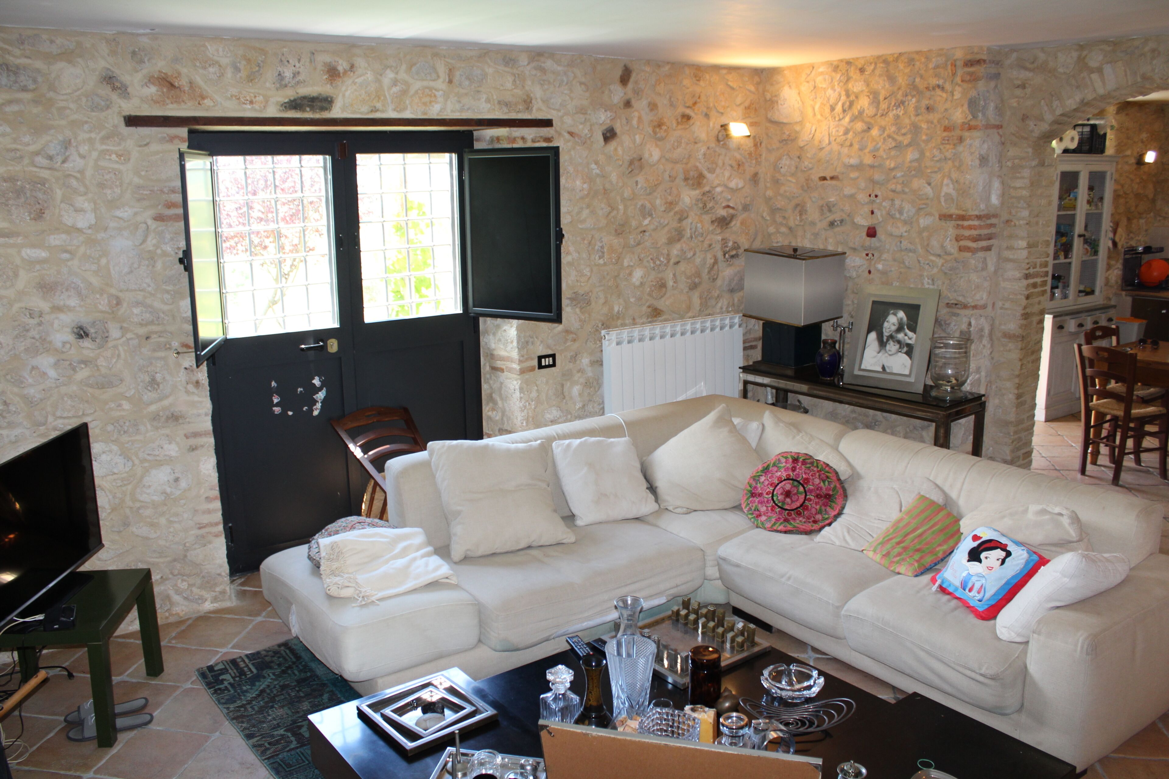 A living room with a white sofa, a television, and a stone wall.
