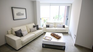 Una sala de estar moderna con dos sofás blancos, una mesa de centro y un cuadro en la pared.