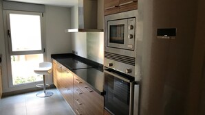 Una cocina moderna con horno empotrado, microondas y electrodomésticos de acero inoxidable.
