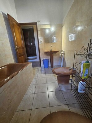 A bathroom with a bathtub, toilet, sink, and a metal rack holding toiletries. - Typical old-fashioned 1711 mill  (Olmeto)