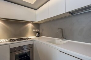 A modern kitchen with a gas stove, oven, white countertops, and a sink.