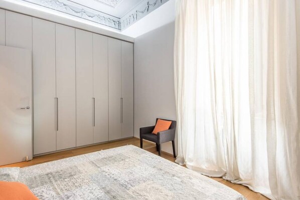 A bedroom with a large wardrobe, a chair, and a bed.