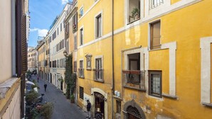 Una calle estrecha flanqueada por edificios amarillos, con un sendero adoquinado y una persona caminando.