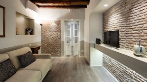 Una sala de estar moderna con una pared de piedra, un televisor de pantalla plana, un sofá y un techo de madera.