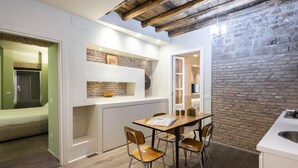 Una cocina compacta con comedor, pared de piedra y techo de madera.