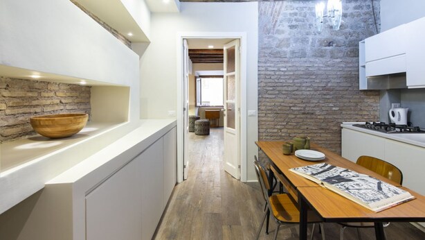 Una cocina con una mesa de madera, una pared de piedra y una encimera blanca.